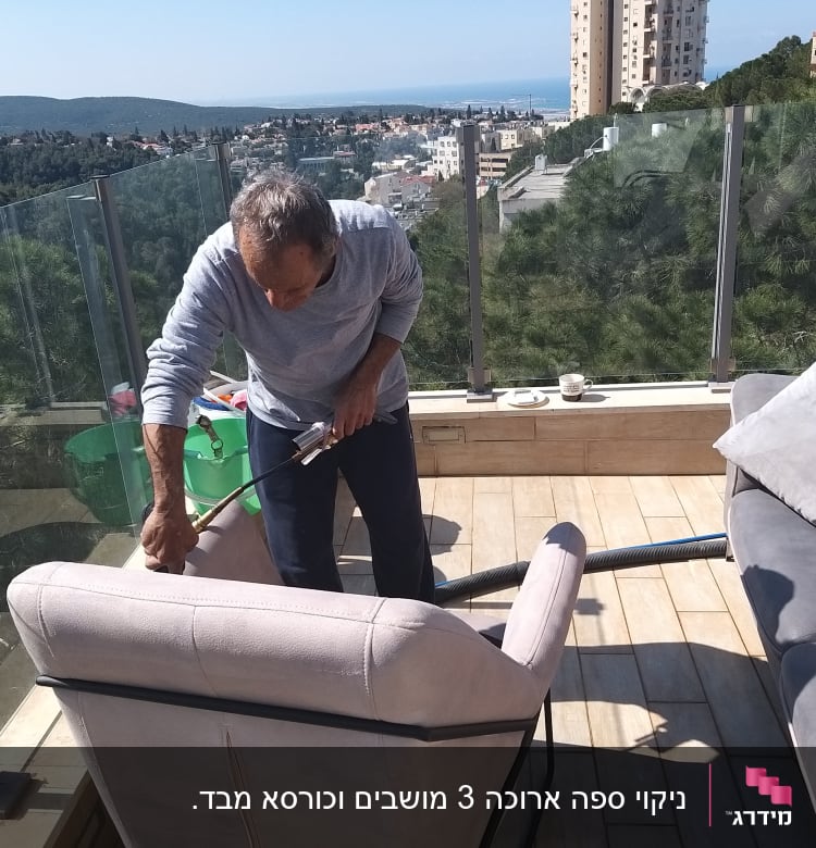 אדם מנקה ספה עם שואב אבק במרפסת